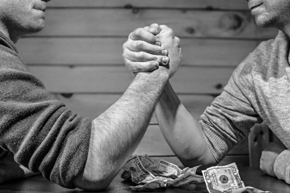 Deux mains qui s'affrontent en bras de fer sur une table en bois