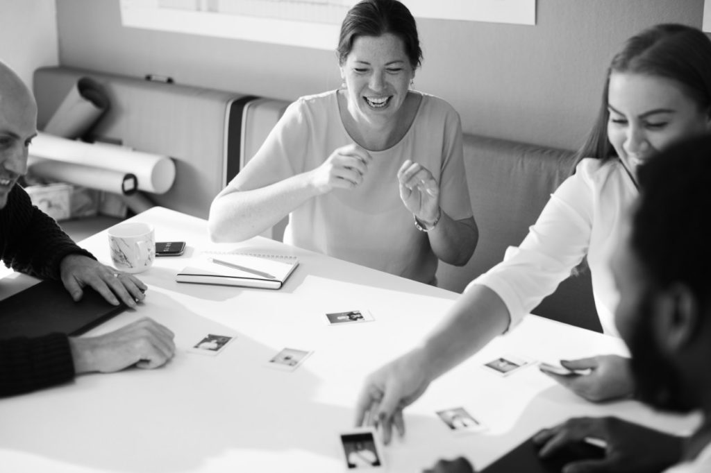 Équipe souriante autour d'une table couverte de documents de travail