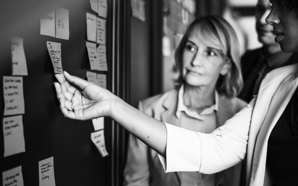 Femme présentant un mur de post-it à son équipe