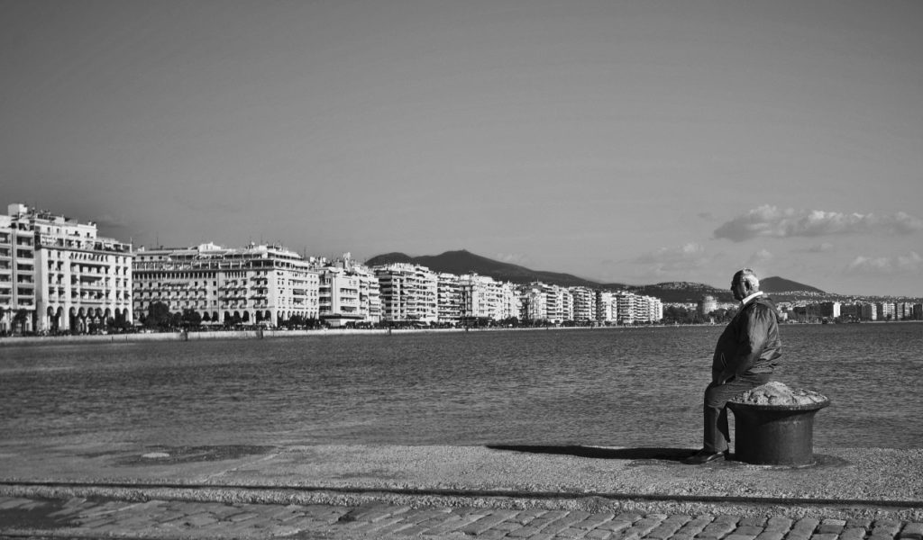 Personne assise seule face à la mer sur une promenade de bord de plage