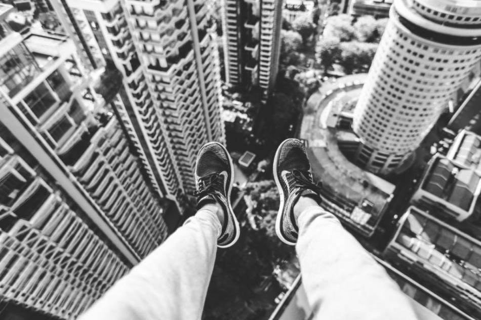 Pieds au bord d'un toit d'immeuble, vue plongeante sur la ville
