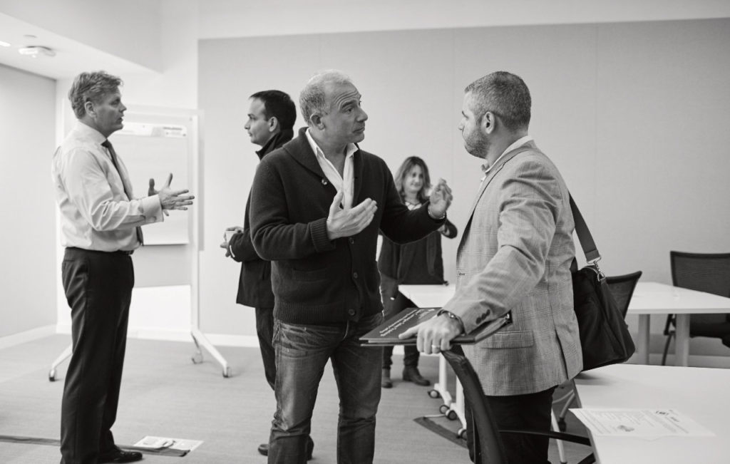 Trois personnes debout en discussion dans un espace de travail