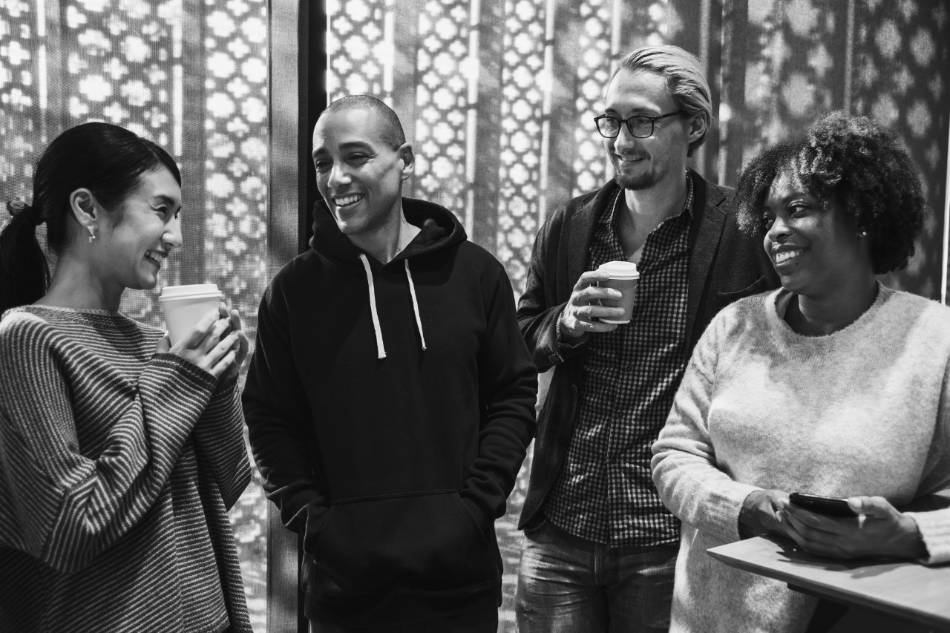 Collègues debout en discussion, gobelets de café à la main