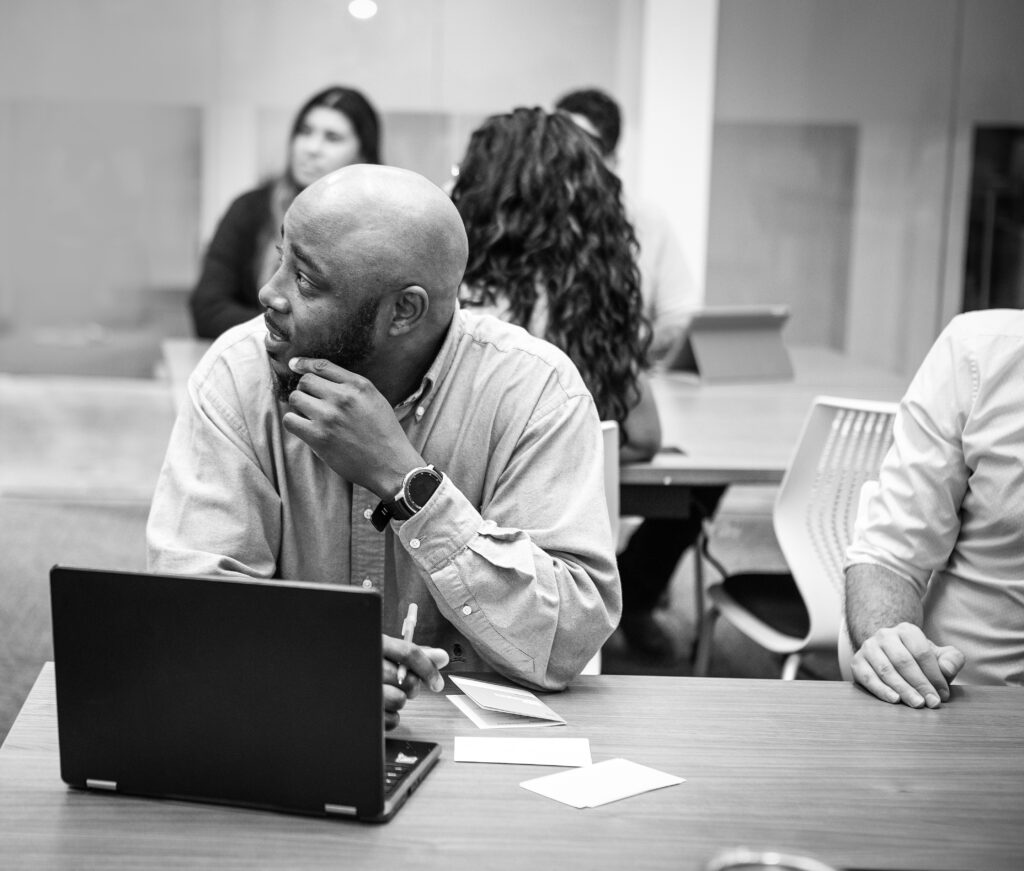 Formateur et participants en échange autour d'un ordinateur portable